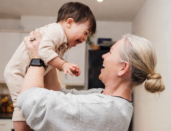 A grandmother lifting a laughing toddler into the air